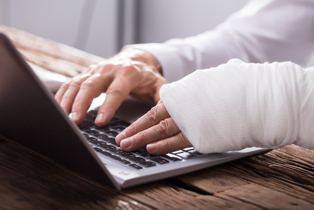 Person With Both Hands Broken Typing On A Laptop